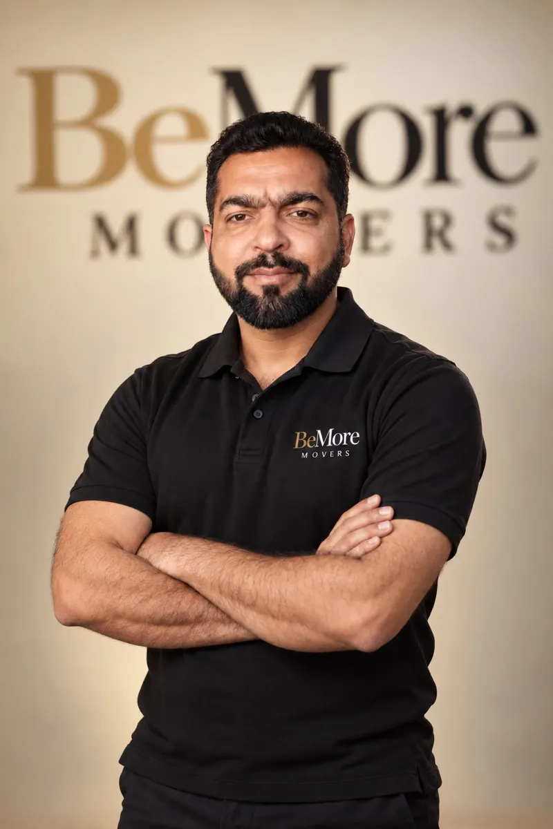 Rana, Head of Logistics at BeMore Movers, arms crossed in a black BeMore Movers polo